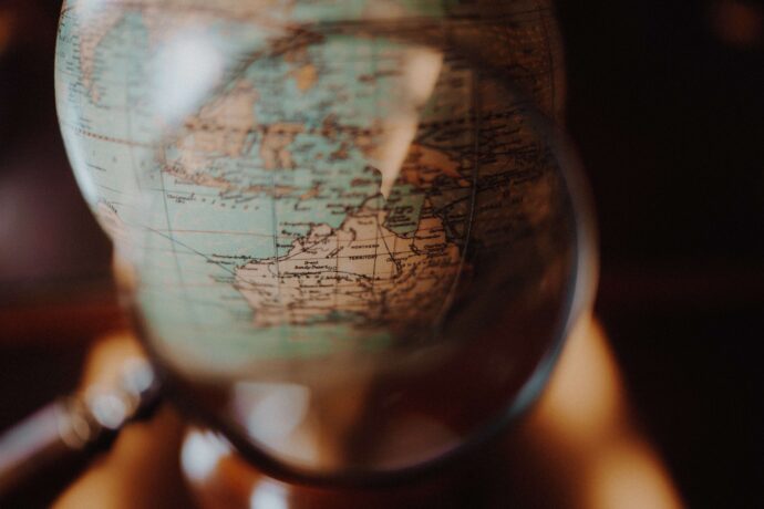 a vintage globe on the background with a magnifying lense, creating the impression of getting close to Australia. Reflecting the action to look closer to home for this International Migrants Day.