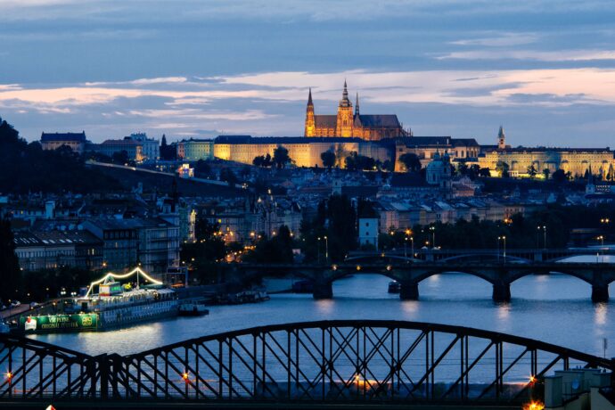 Image at sunset of Prague in Czech Republic. Two bridge are at the front and the city center lit up at the back.